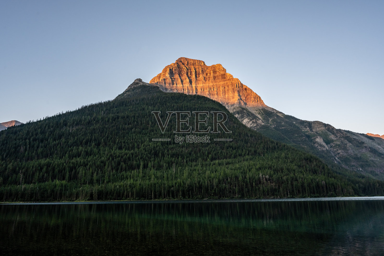 金纳利峰耸立在上金特拉湖和深绿色山脊之上照片摄影图片