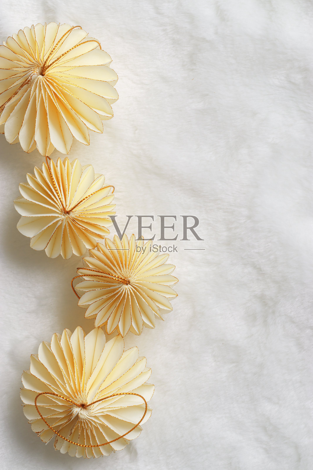 新年装饰品，金色圣诞闪光灯形状的球体放在白色毛皮和柔软褶皱的背景上，简约布局，纸质节日装饰米色球体，现代装饰，俯视图照片摄影图片