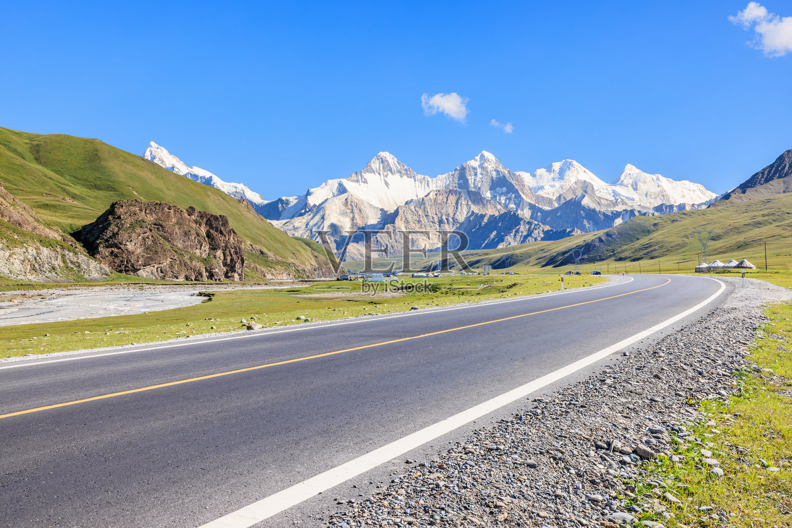 蓝天下的沥青高速公路与绿色草地，雪山自然风光。照片摄影图片