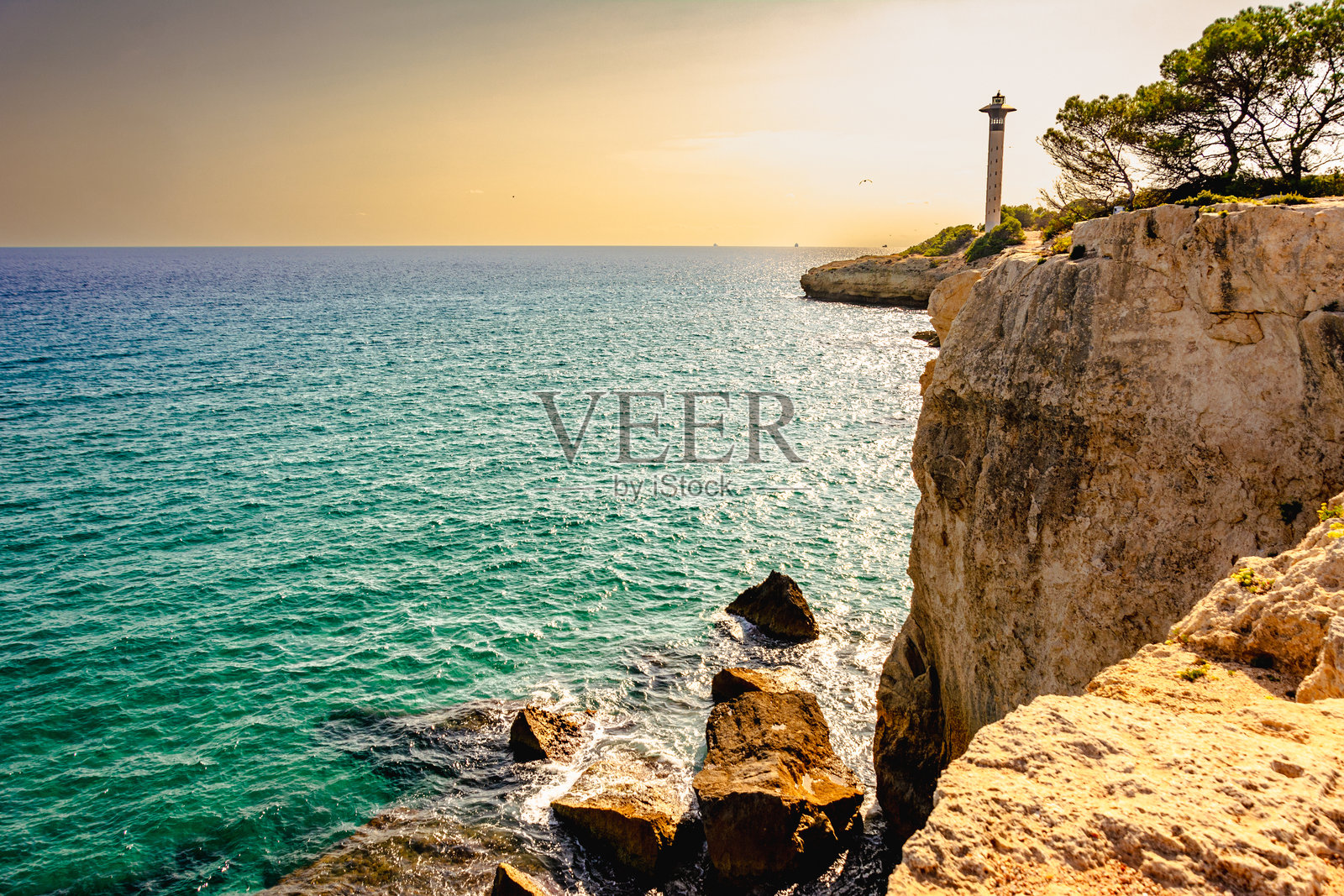 崎岖的悬崖和灯塔俯瞰生机勃勃的蓝色海洋照片摄影图片