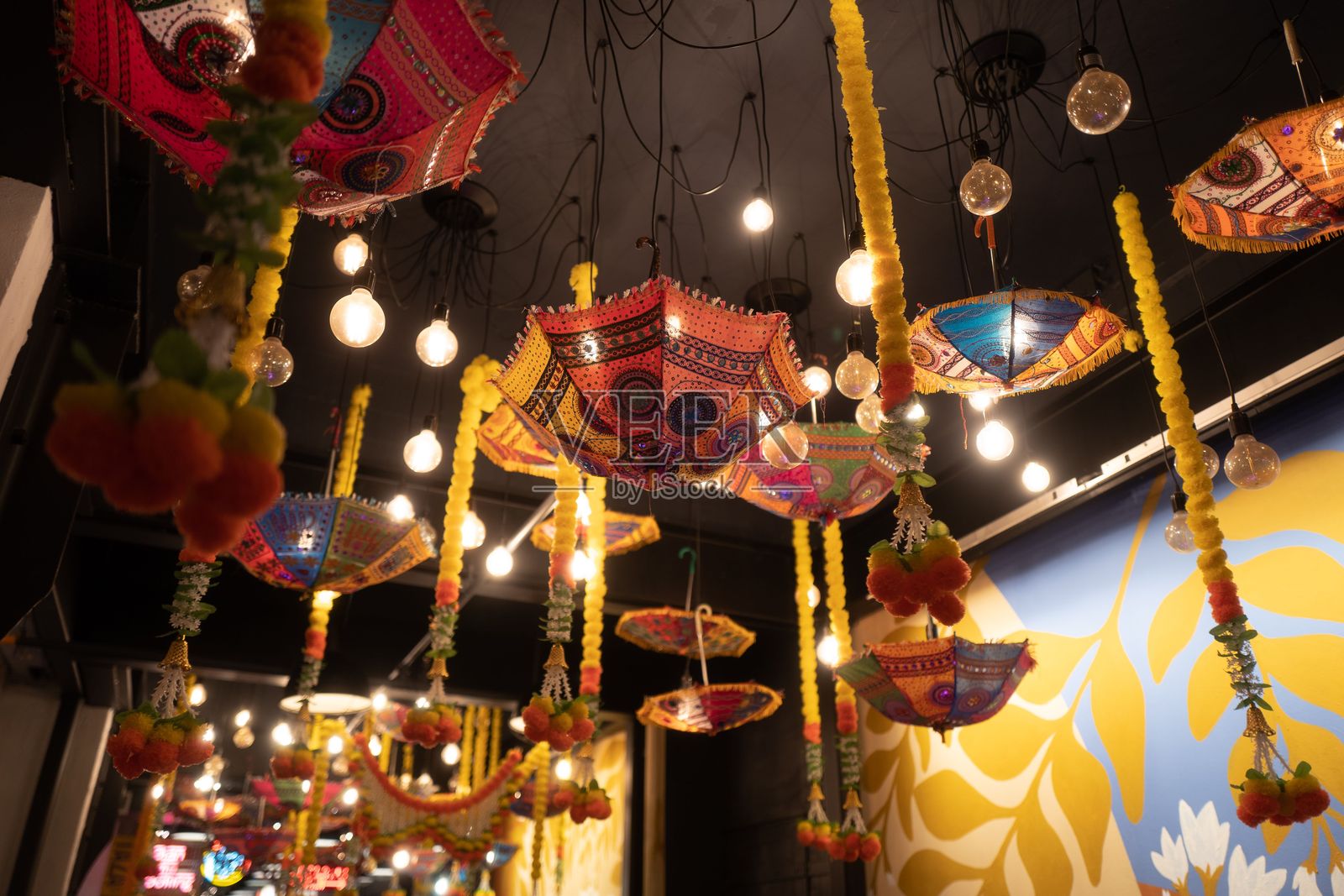 色彩斑斓的伞展示，悬挂在天花板上，配有传统印度图案和灯具照片摄影图片
