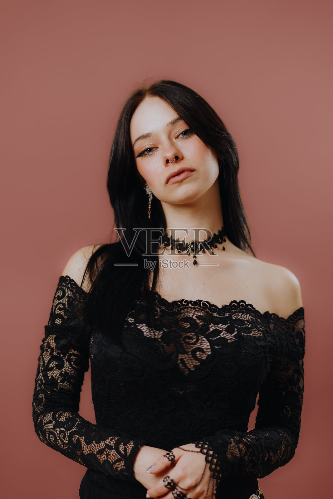 年轻女性哥特风模特在工作室中穿着黑色服装和珠宝摆姿势照片摄影图片