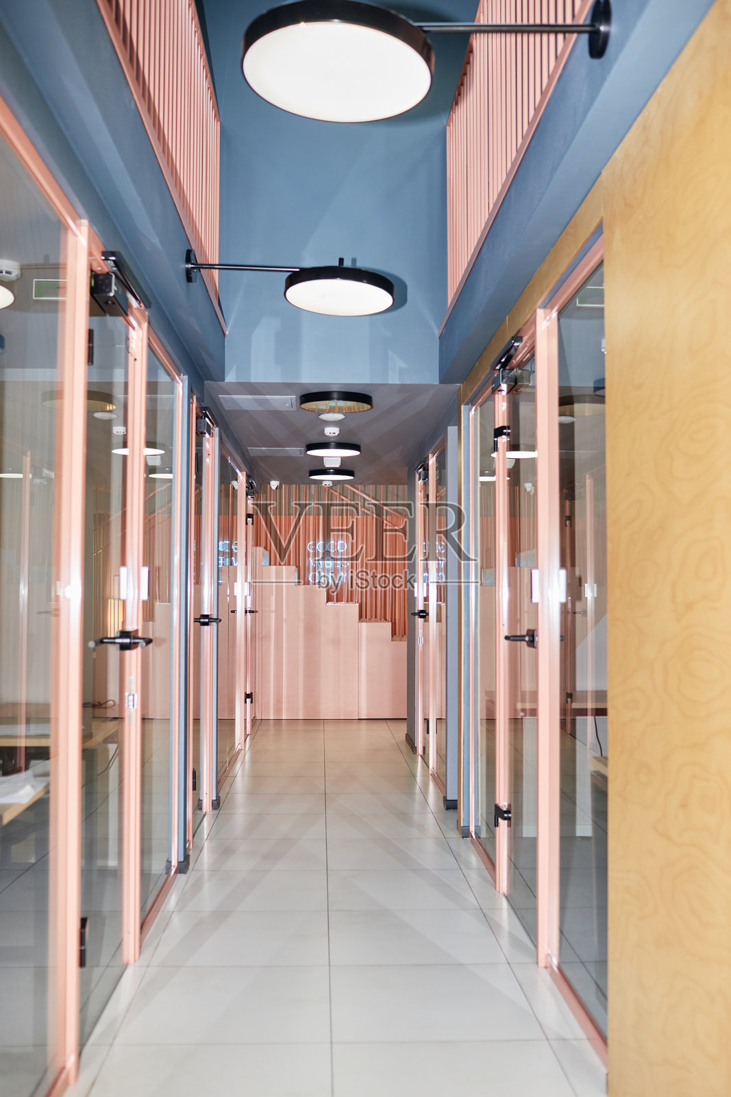 商务中心内的走廊，玻璃门通向粉色设计的办公室房间照片摄影图片