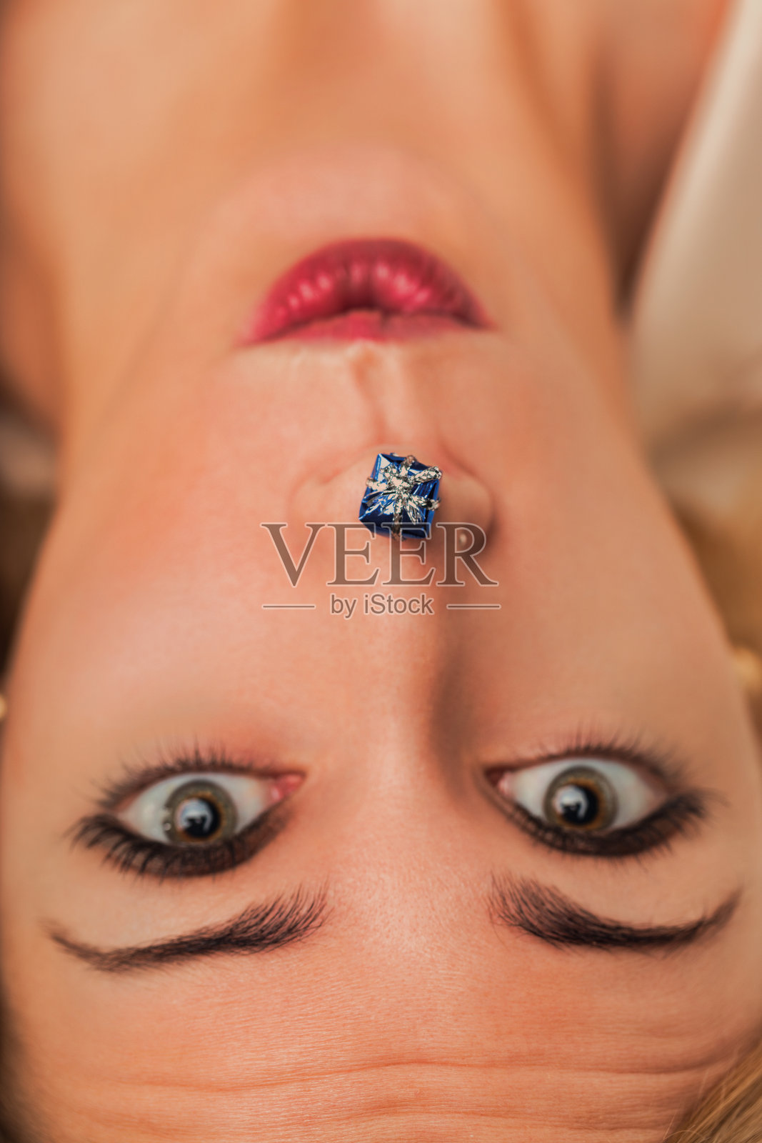 女人看着放在她鼻子下的小礼物照片摄影图片