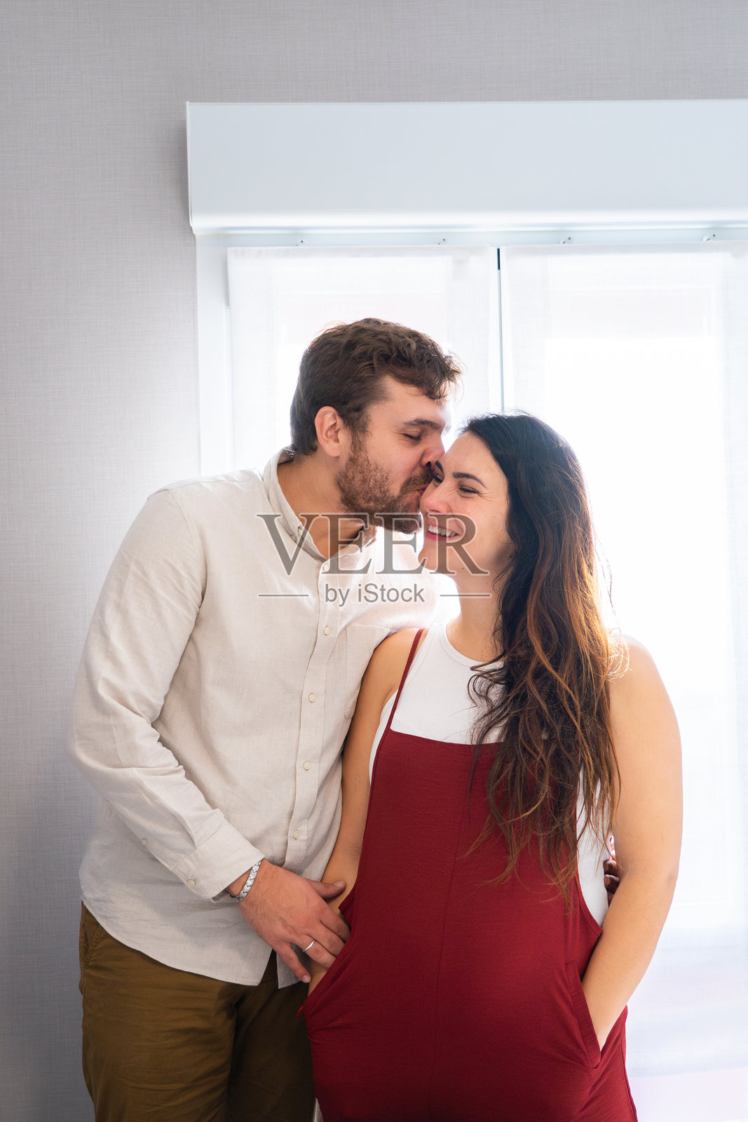 男人在家里亲吻他的孕妻照片摄影图片