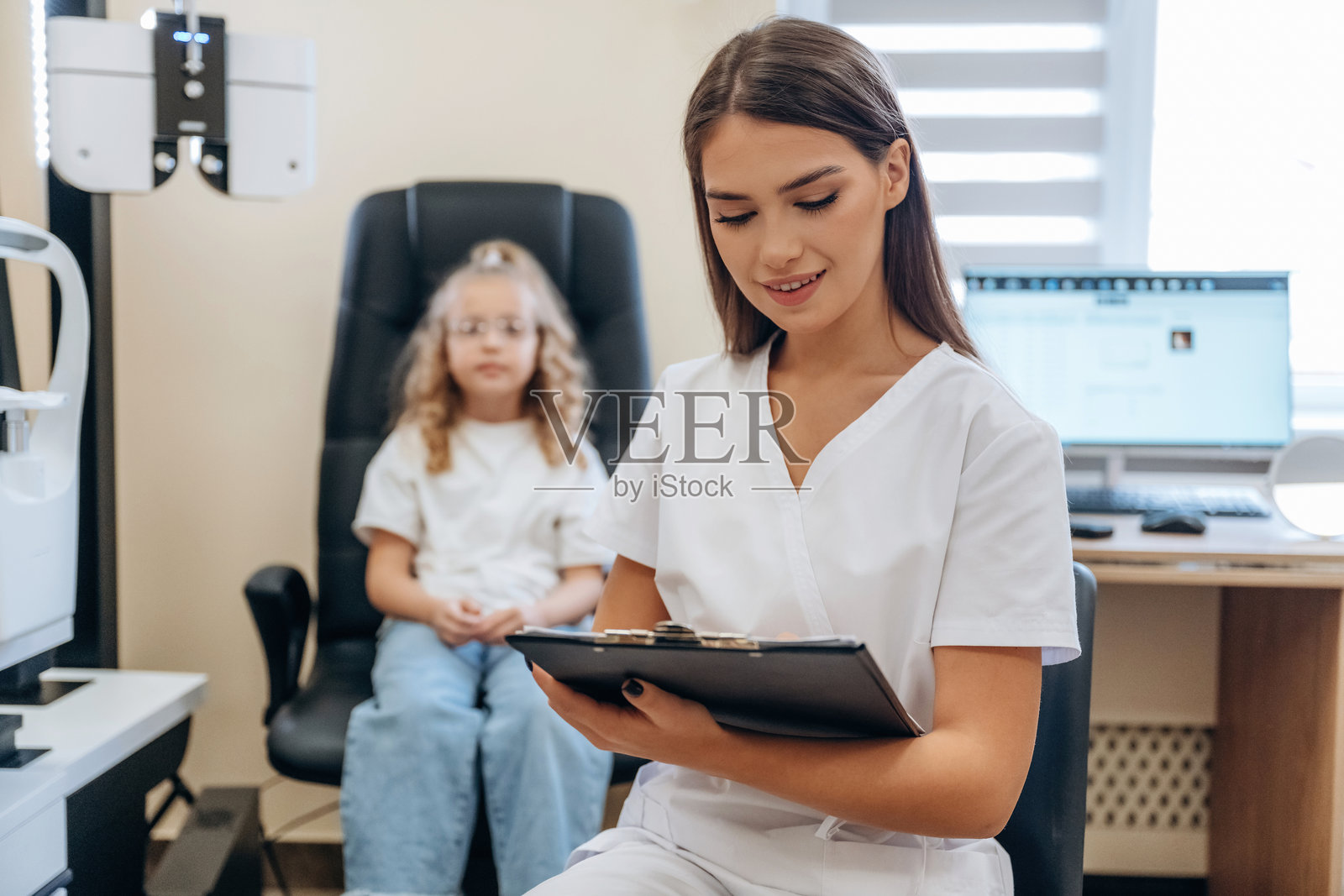 手握记事本的小女孩在眼科诊所与医生在一起照片摄影图片