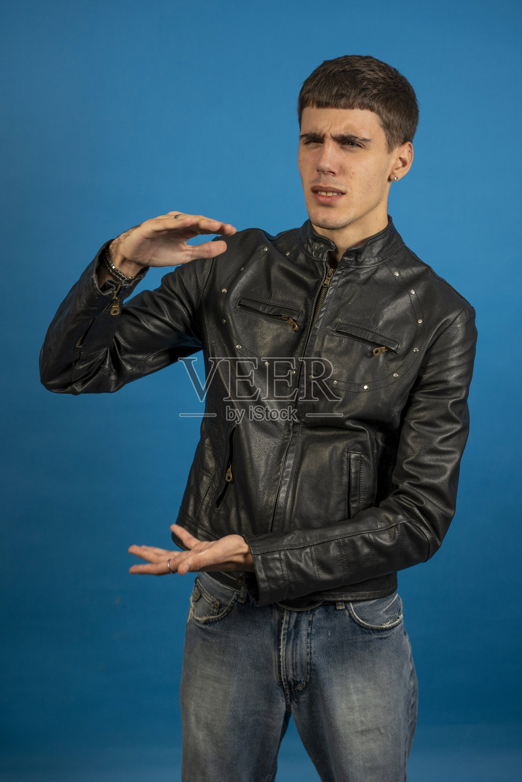 青少年男子指向蓝色背景上某个大型物体照片摄影图片