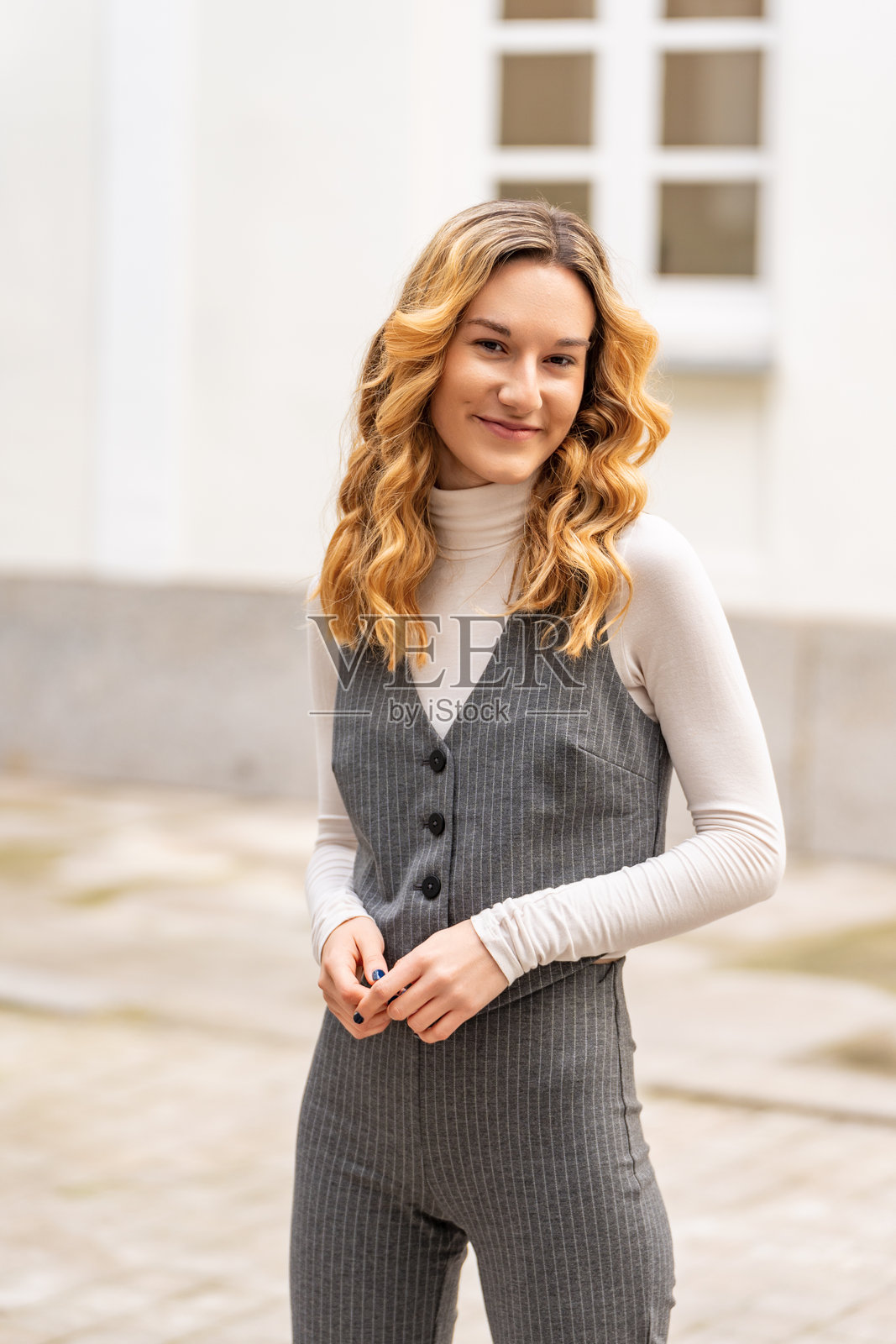 年轻的金发女商人在城市环境中穿着优雅的条纹西装微笑照片摄影图片