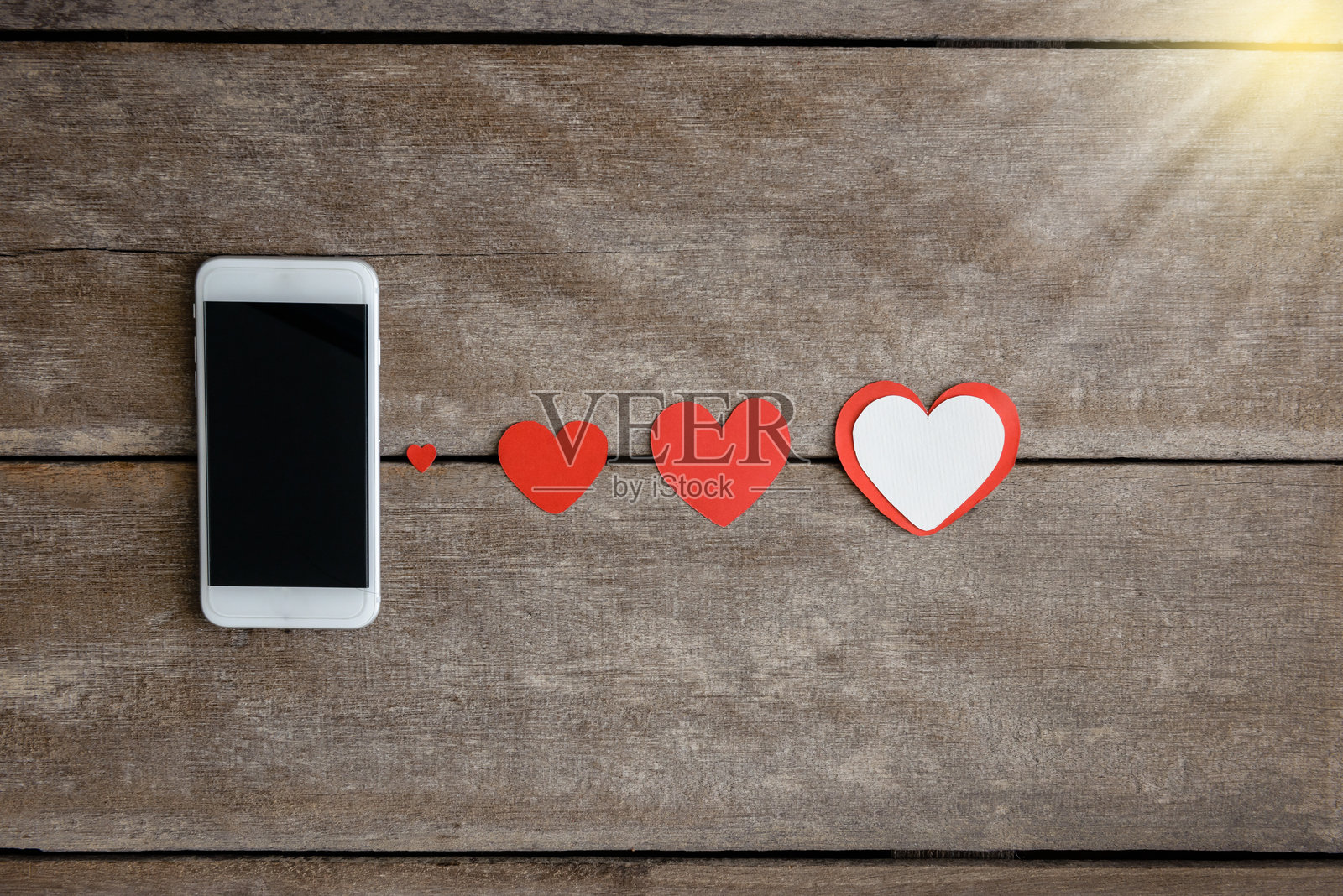 智能手机旁桌子上的红色心形图案俯视图照片摄影图片