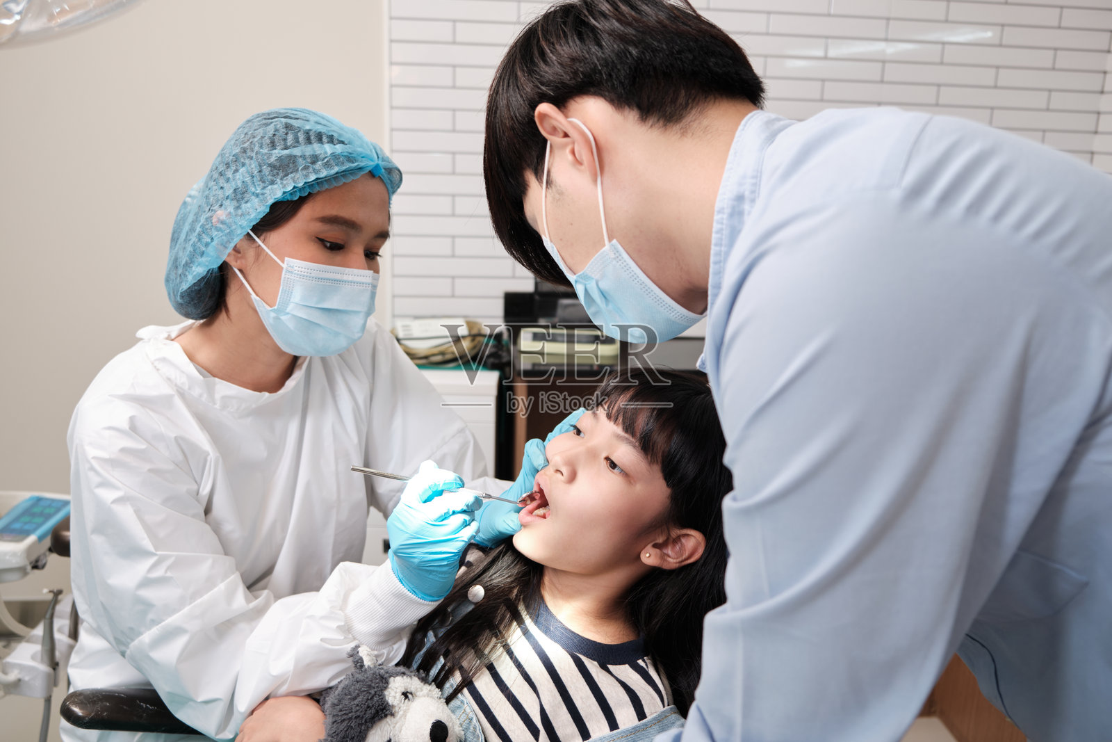 亚洲女性牙医在牙科诊所检查和检查女孩的牙齿。照片摄影图片