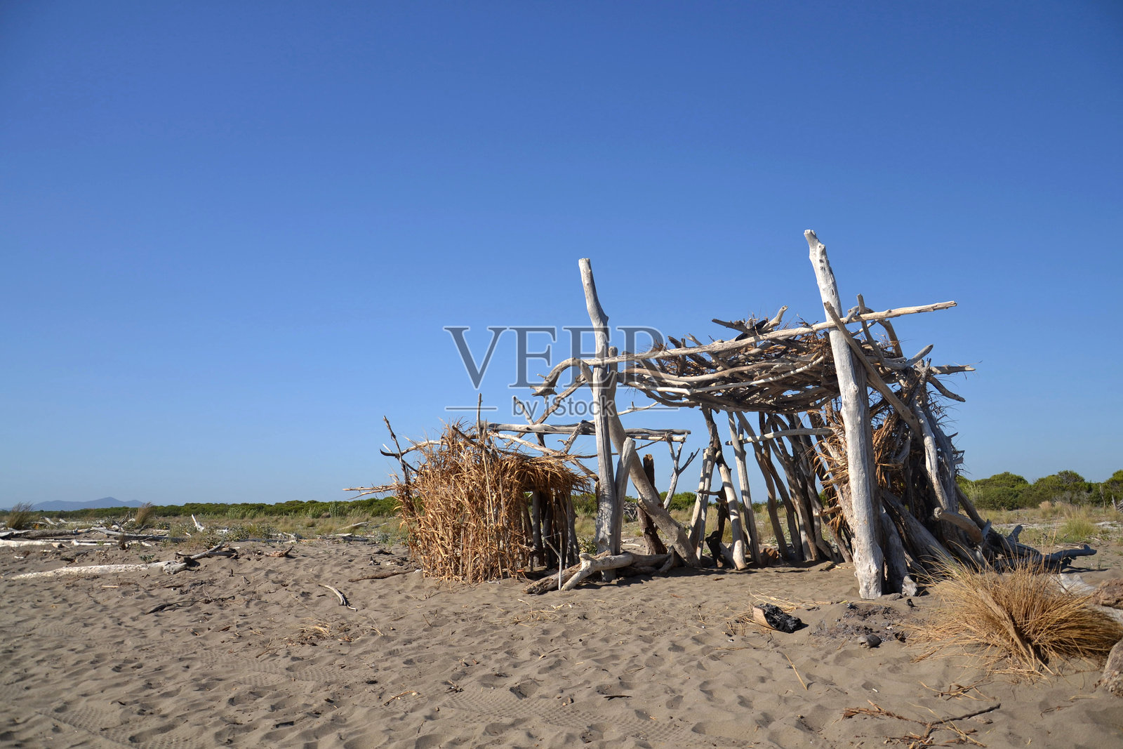 在意大利托斯卡纳的马里纳·迪·格罗塞托海滩，使用冲刷上岸的木材建造的抵御风和阳光的木质避难所照片摄影图片