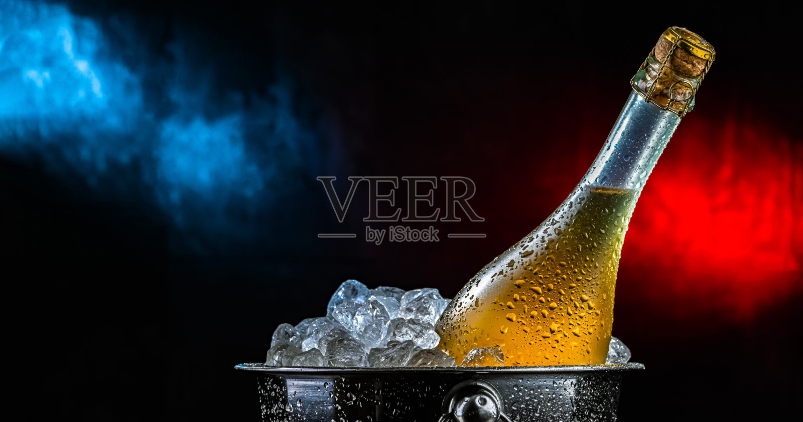 装有碎冰的桶中盛放着一瓶起泡酒。照片摄影图片