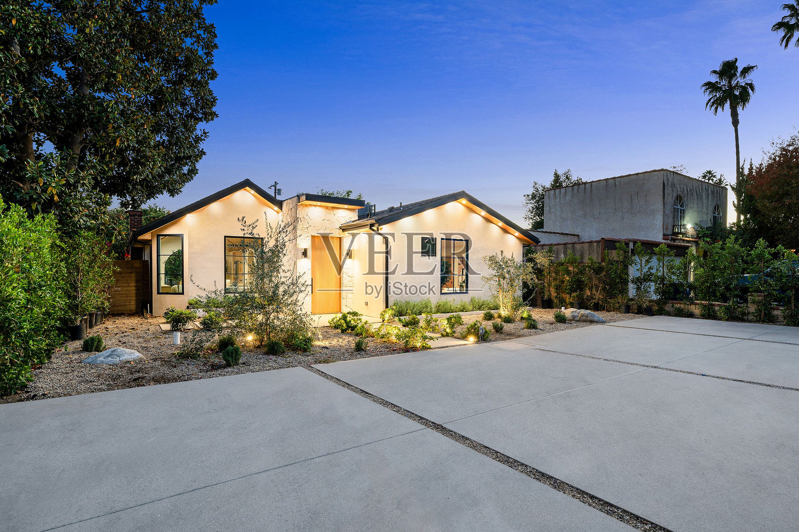 黄昏时分，现代房屋的灯光外立面。照片摄影图片