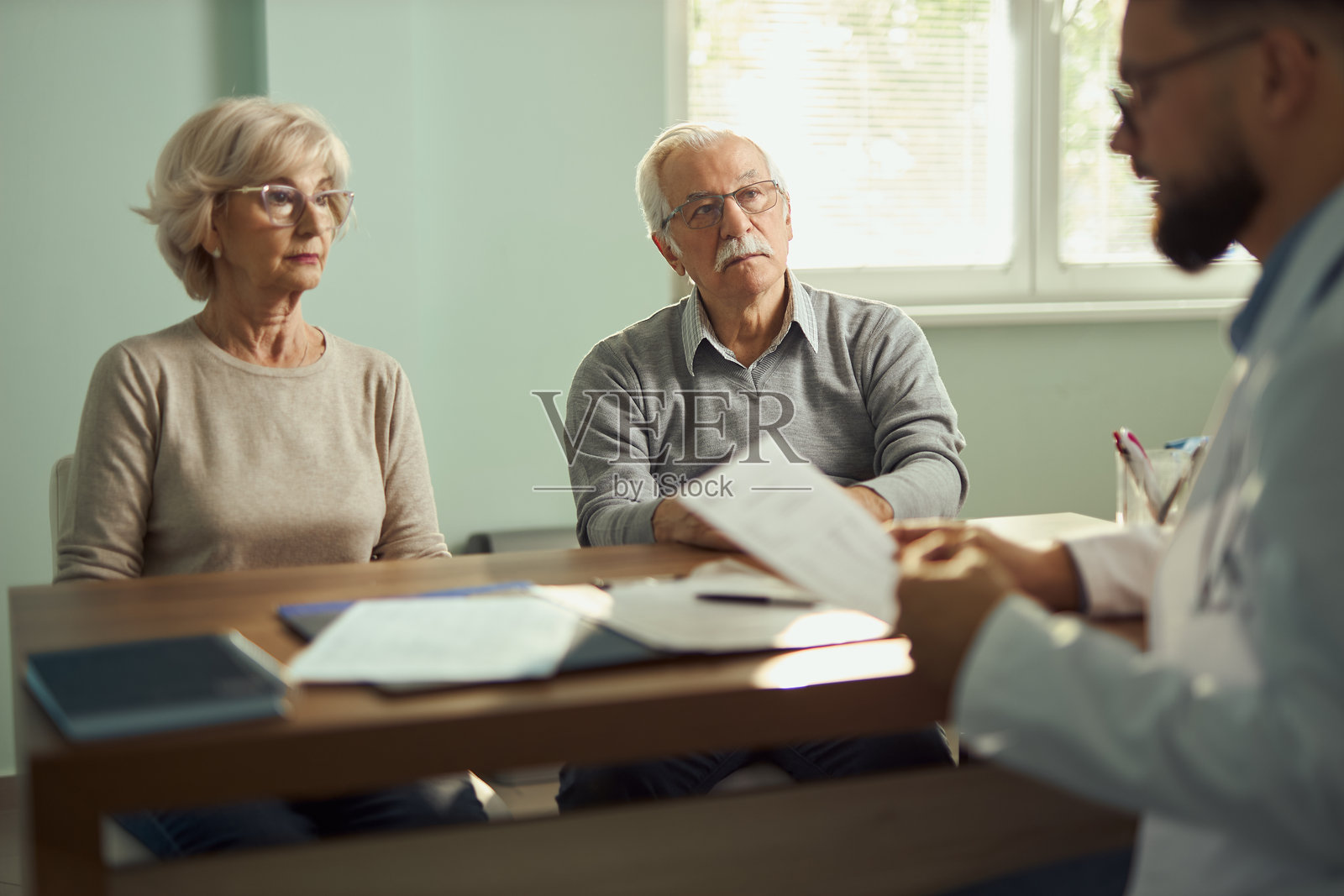 成熟夫妇在医院看医生。照片摄影图片