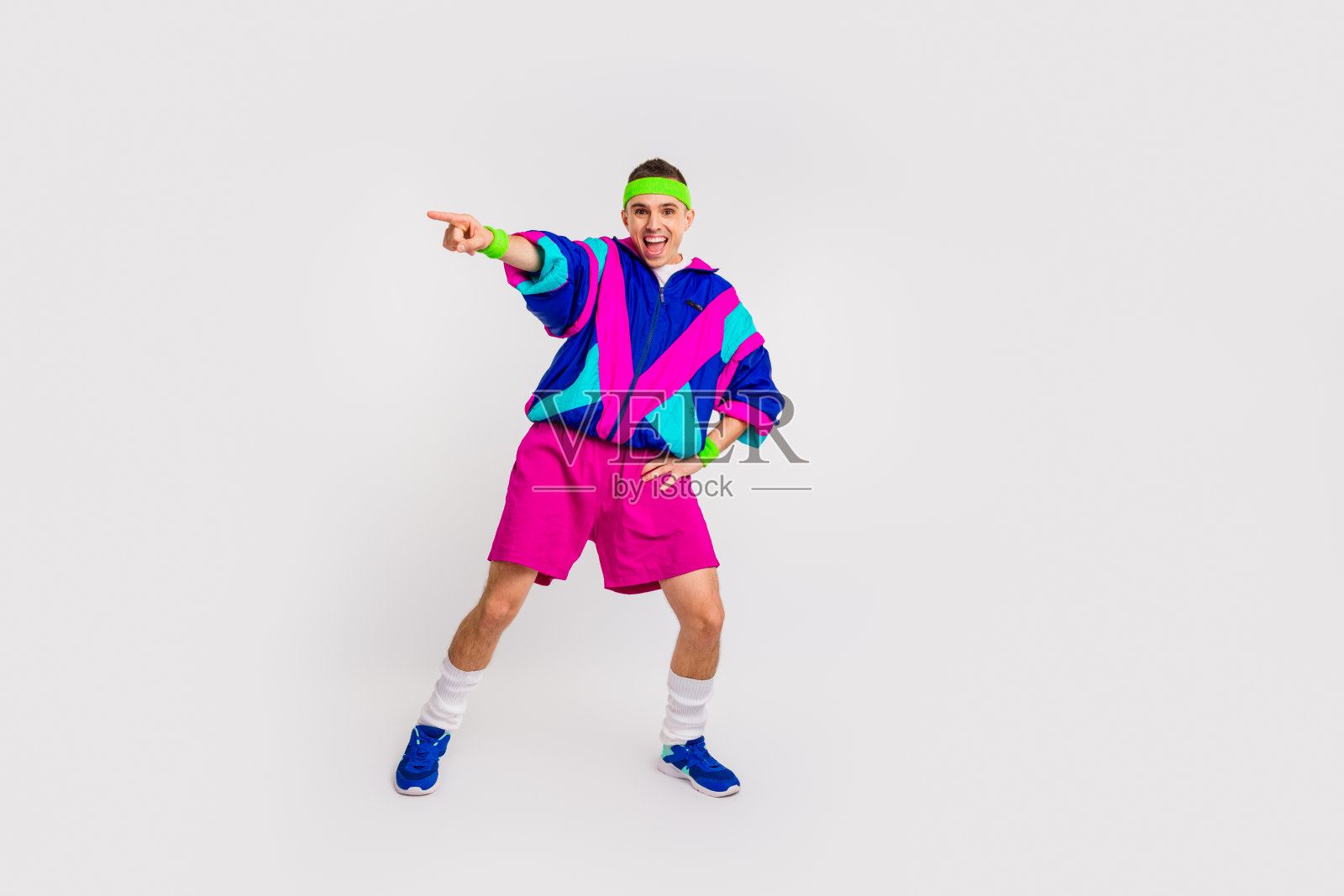 充满活力的年轻男子穿着鲜艳的复古运动服，在简约的白色背景下展示生动的舞蹈动作照片摄影图片
