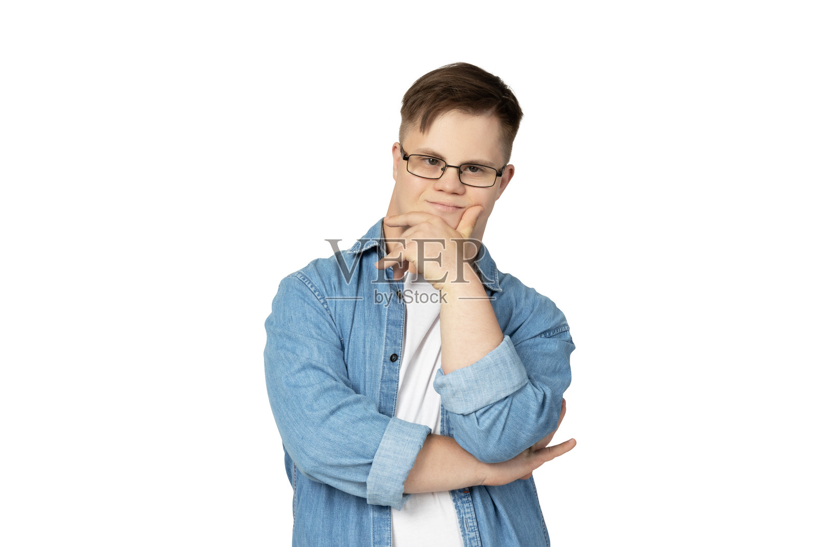 戴眼镜、穿牛仔裤和白色T恤的微笑年轻男子，患有唐氏综合症，正在为相机摆姿势，背景为白色。照片摄影图片