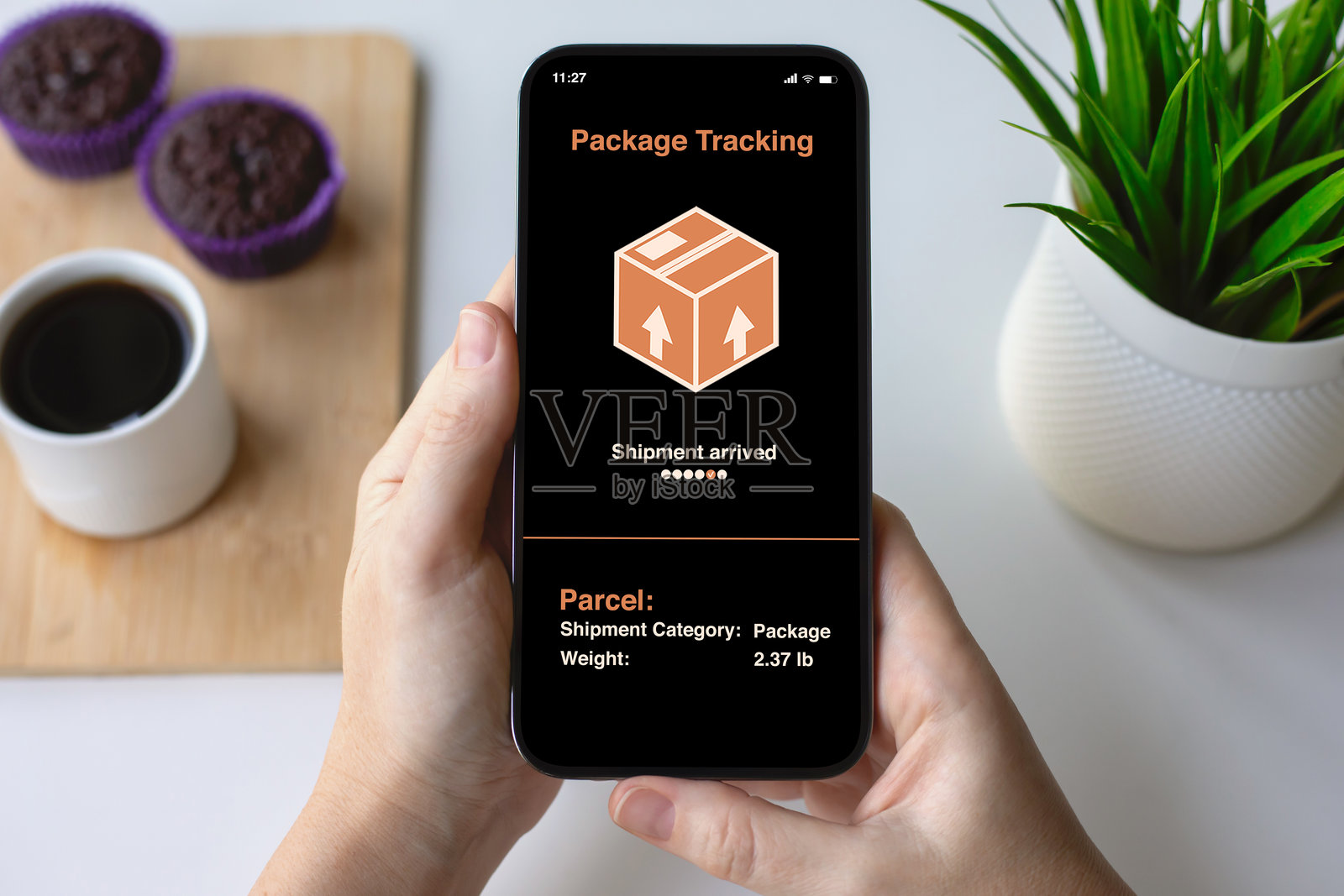 女人的手握着手机，手机屏幕上显示着包裹配送追踪应用。照片摄影图片