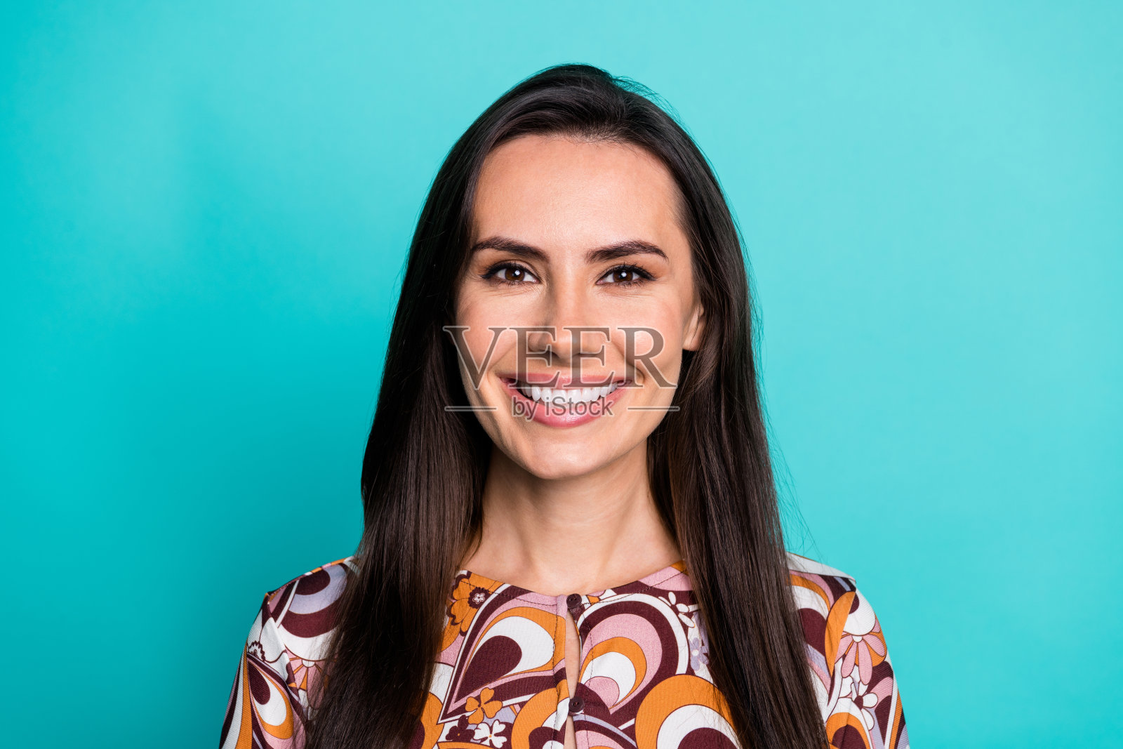 迷人积极的女性穿着印花衬衫，微笑着面对空白空间，背景为青绿色。照片摄影图片