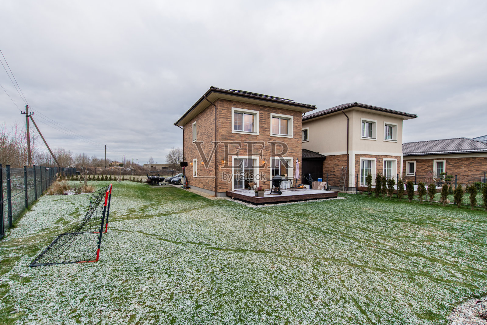 一栋带有露台和车道的砖房。现代砖石和灰泥住宅，宽敞的绿色后院在阴云密布的天空下。房屋外观照片摄影图片