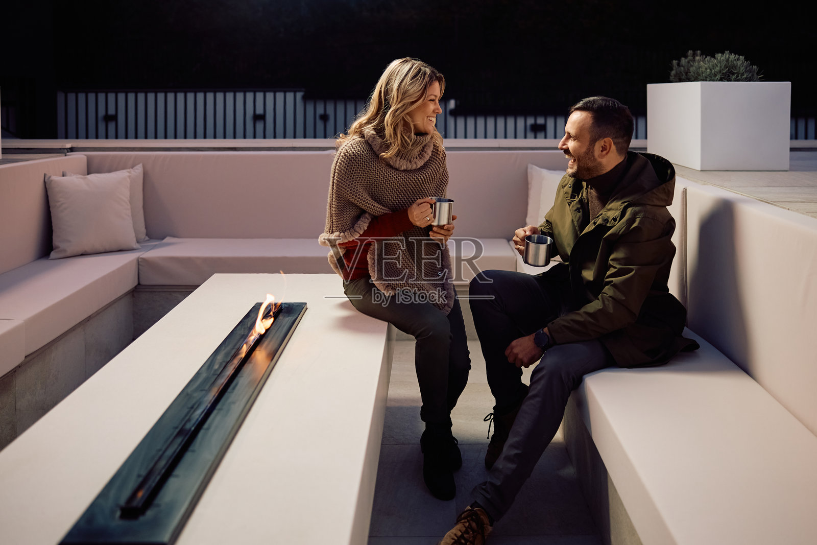 幸福的情侣在露台上围绕壁炉喝茶聊天。照片摄影图片