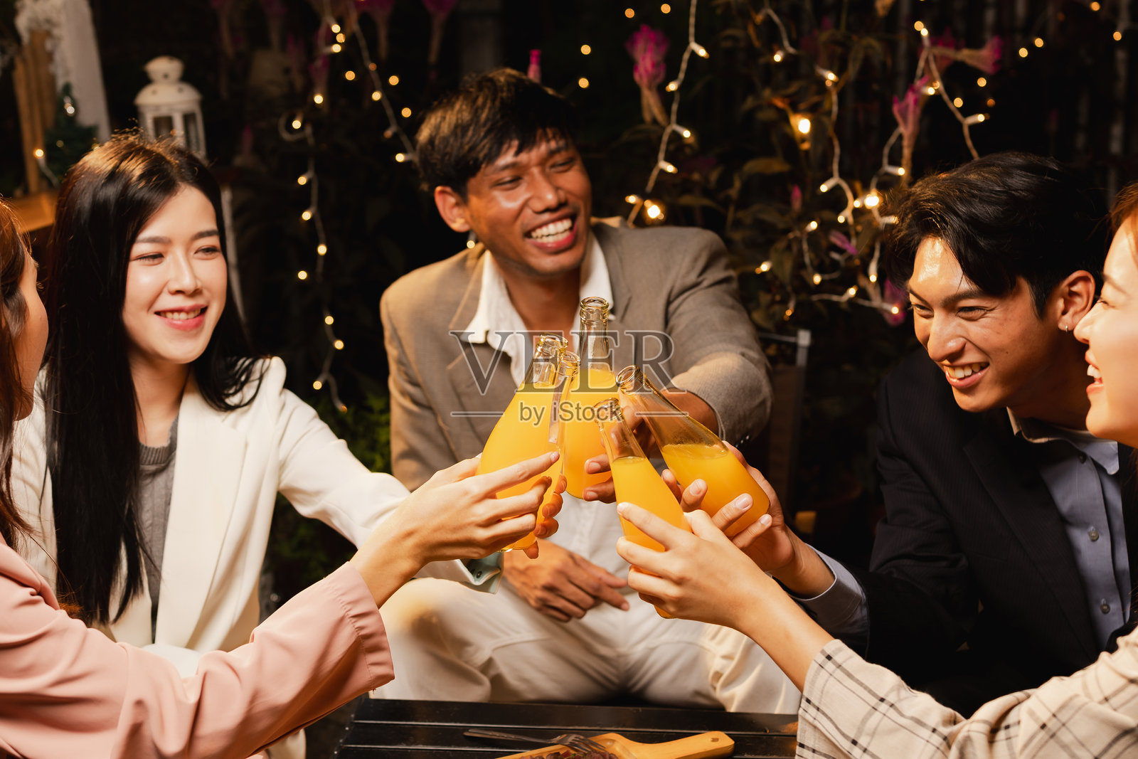 一群朋友在夜晚庆祝时碰杯。照片摄影图片