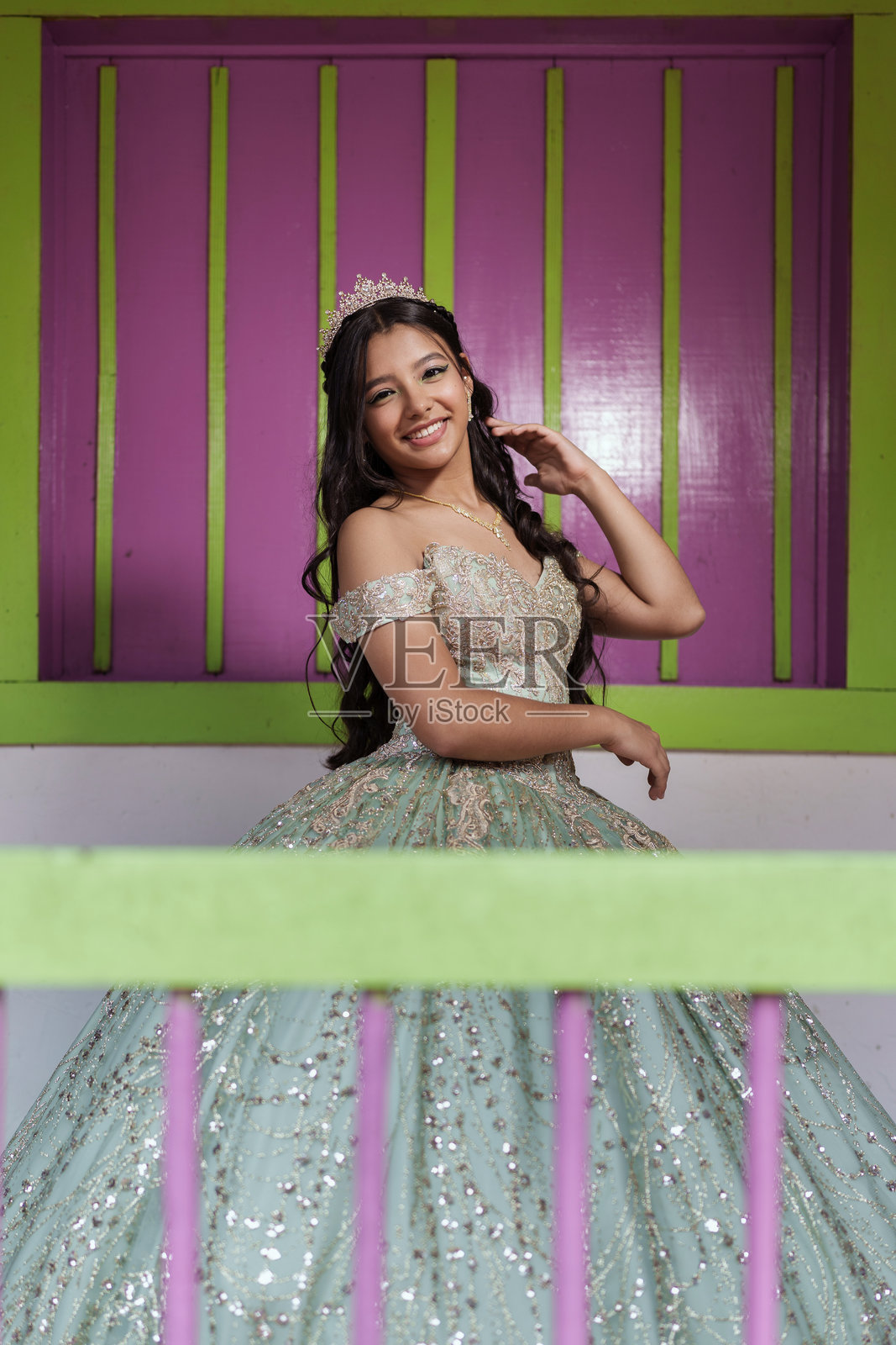 15岁少女穿着优雅的裙子和皇冠，摆姿势庆祝十五岁成人礼。照片摄影图片