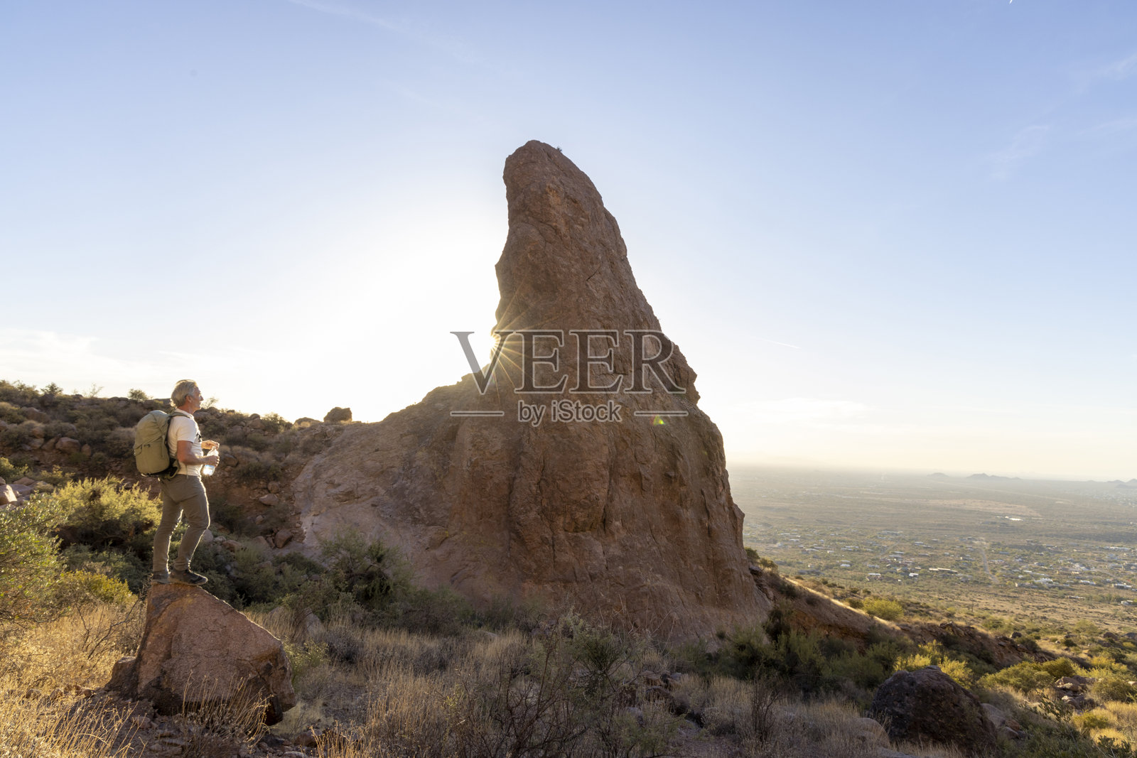 的背包客在尖峰下的岩石上停留照片摄影图片