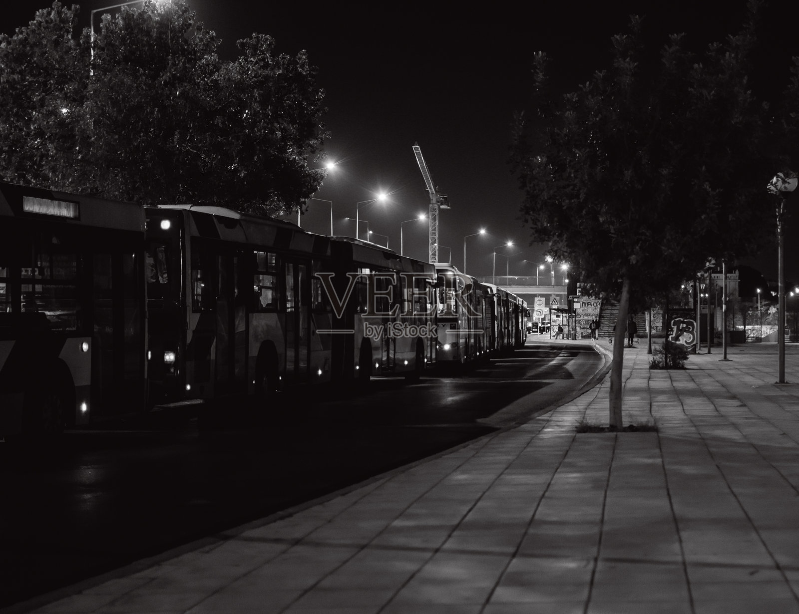 黑白照片显示雅典市的城市公交车在夜晚停靠在高速公路上。照片摄影图片