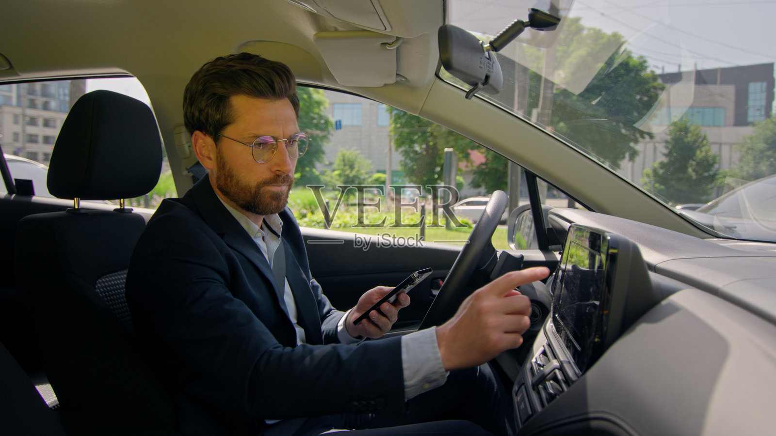 商务人士在现代电动车内驾驶，面露不悦和困惑，因导航错误而担忧，使用手机和GPS应用在交通拥堵中寻找目的地。照片摄影图片