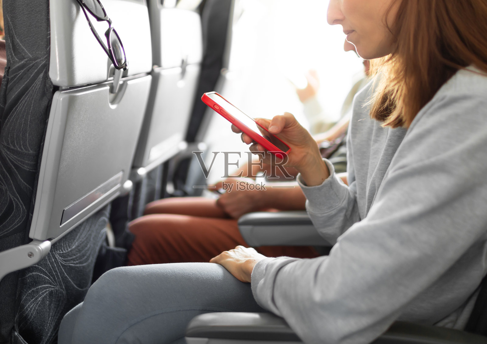 女性旅客在飞机上使用手机。照片摄影图片