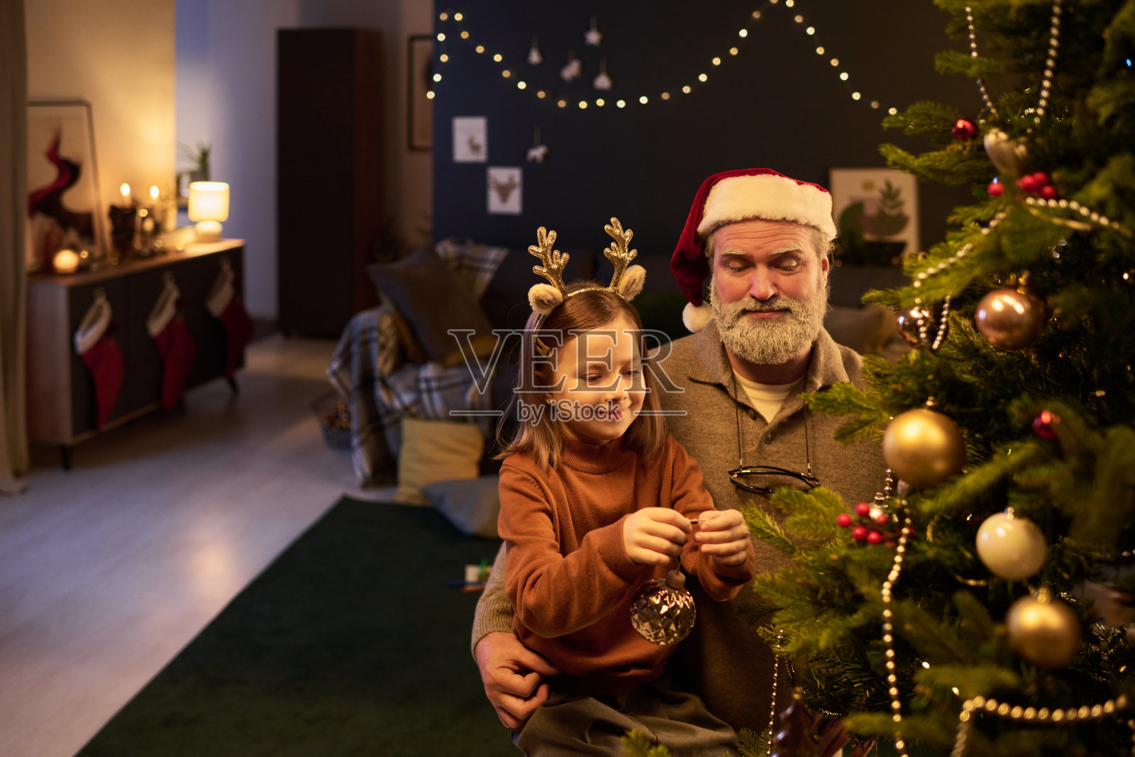 和祖父一起装饰圣诞树，祖父戴着圣诞老人帽照片摄影图片