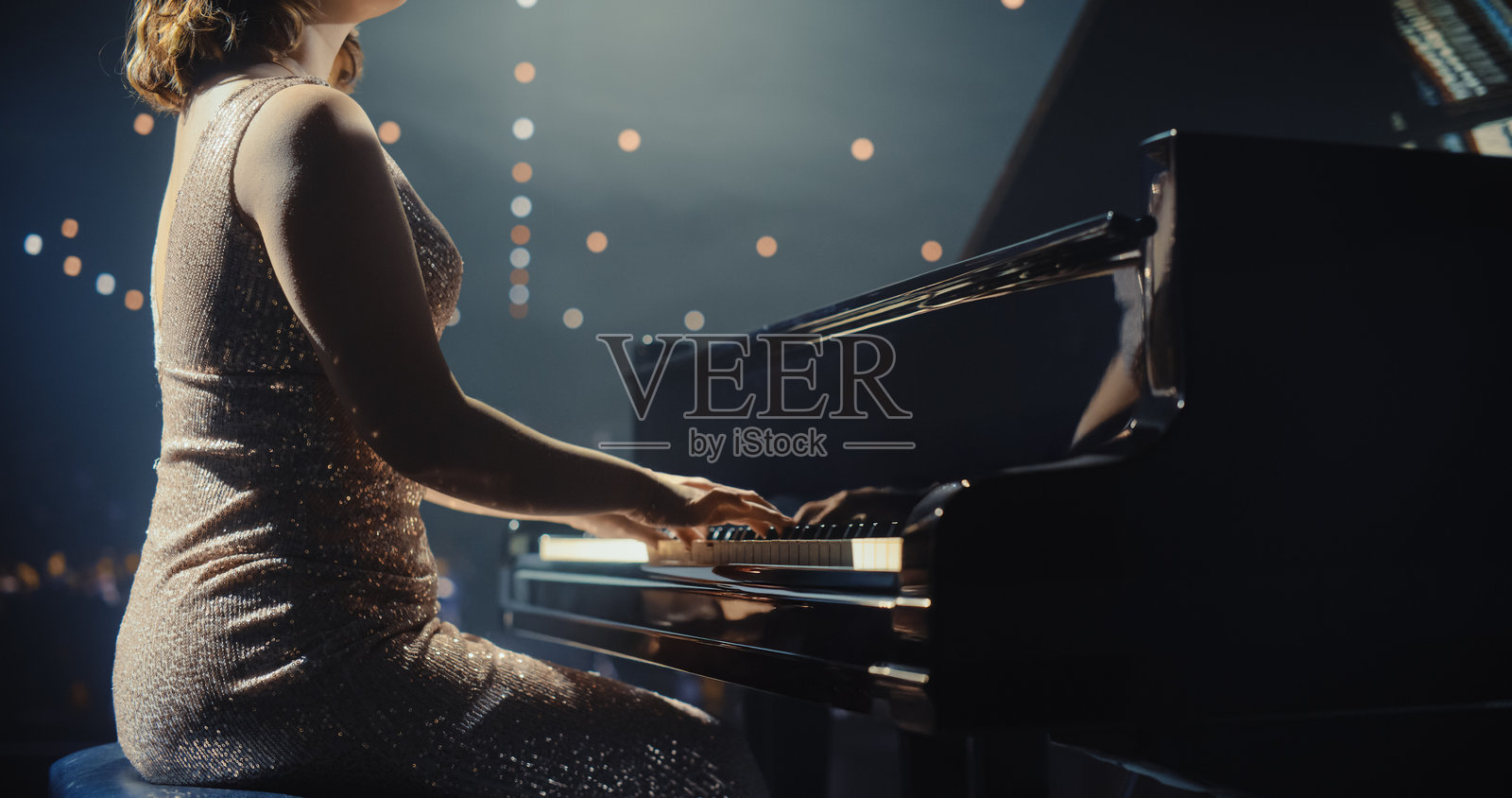 特写镜头：女钢琴家的手在舞台上演奏古典器乐音乐。音乐家使用大钢琴创作美丽的旋律即兴演奏。观众坐在音乐厅中。照片摄影图片