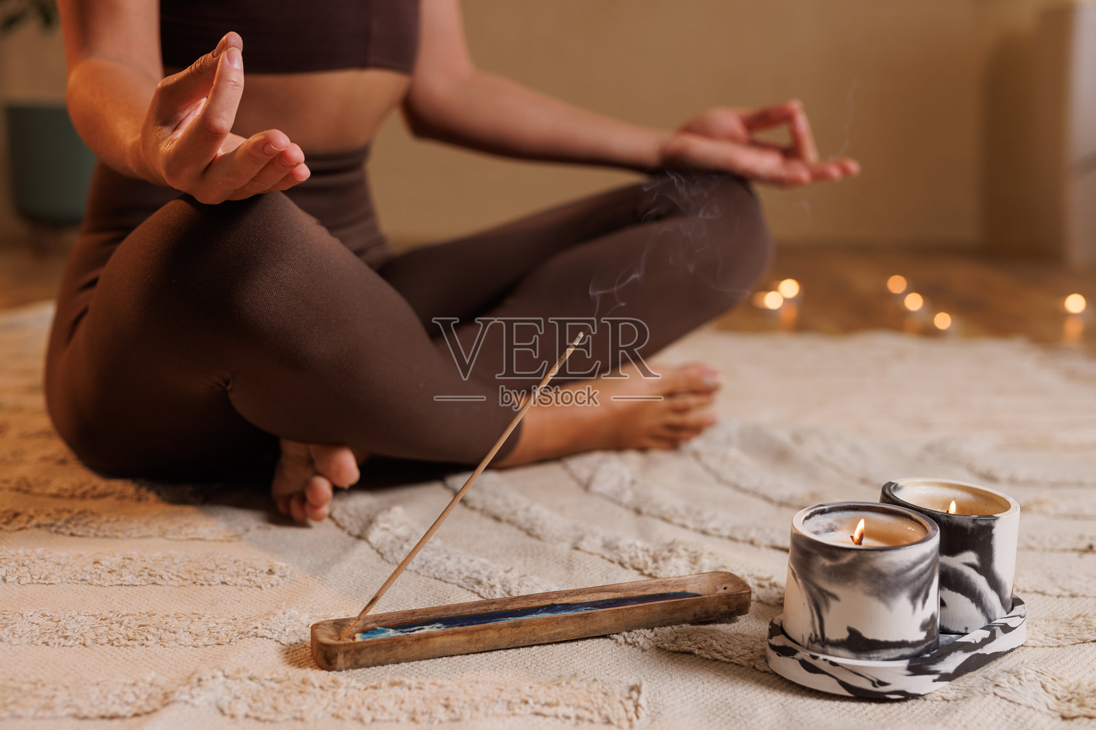 专注的女性在冥想，手持燃烧的香棒，盘腿而坐。双手放在膝盖上，手掌朝上。照片摄影图片