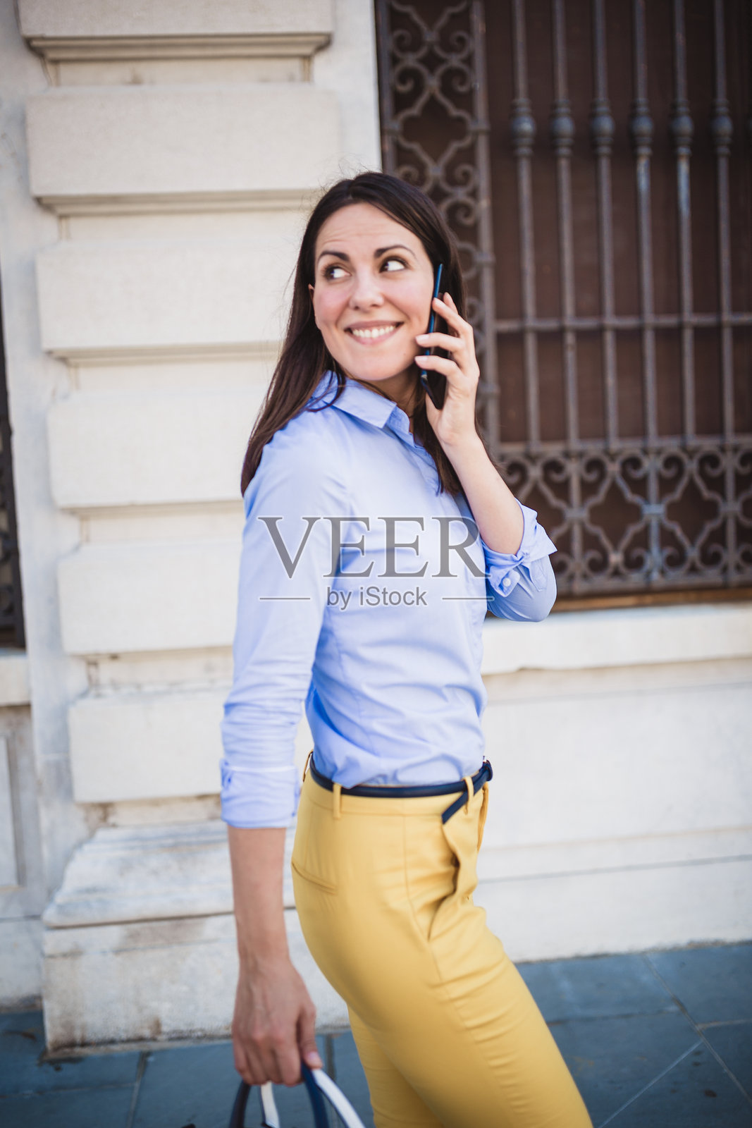 城市环境中与电话交谈的职业女性照片摄影图片