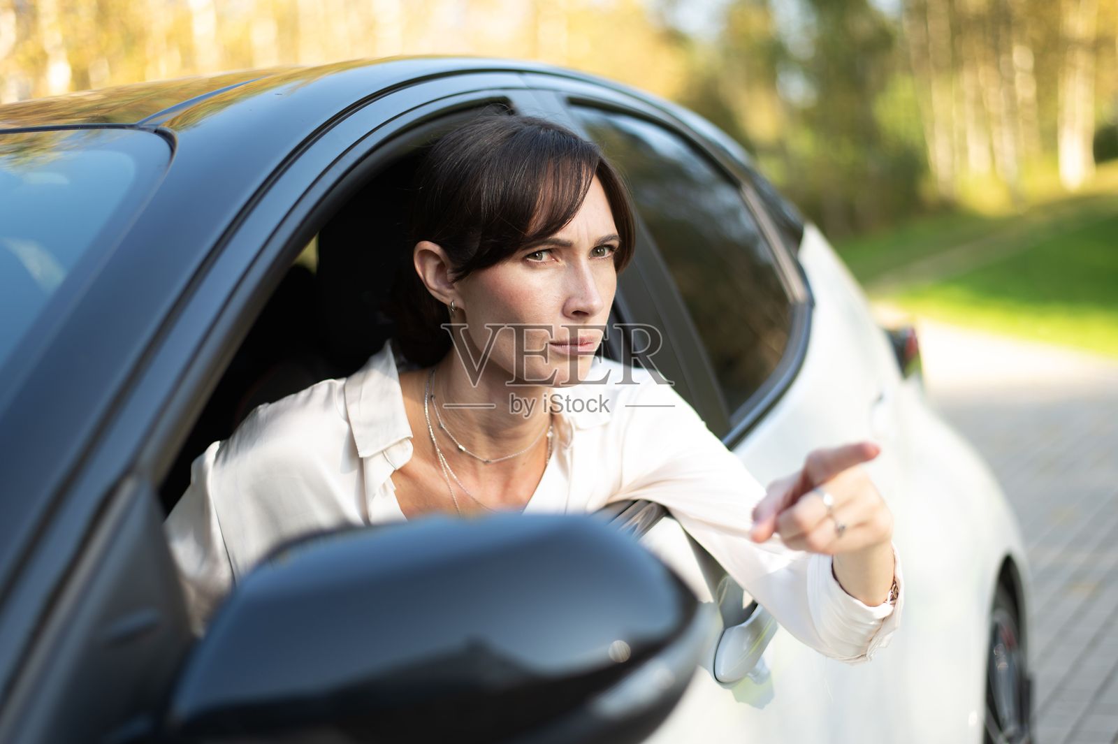 30多岁的白人女性坐在车里，用手指指着某处照片摄影图片