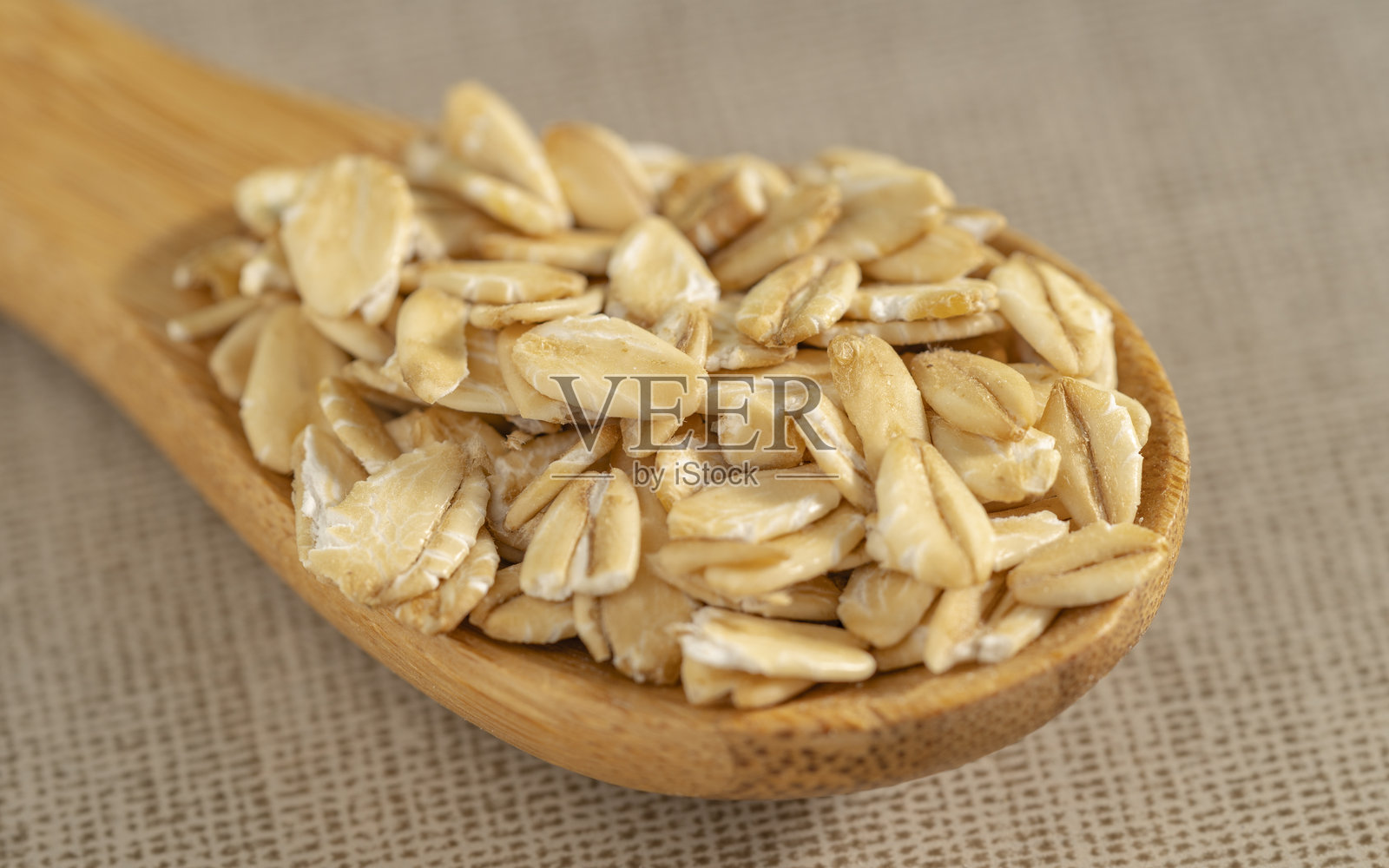 木勺上的燕麦片，背景为米色纹理布料照片摄影图片