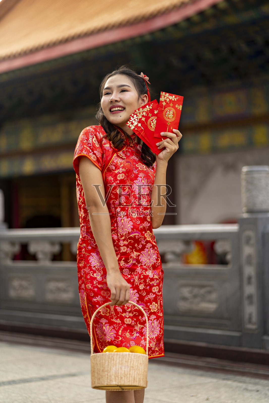 身穿红色旗袍的年轻亚洲女性手持春节象征物照片摄影图片