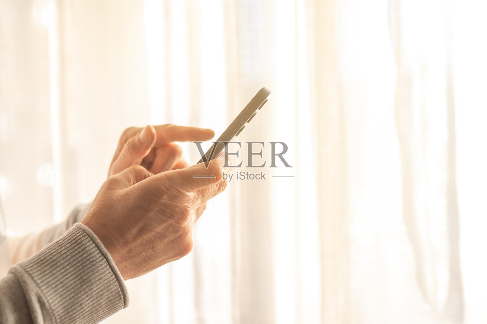 靠近窗户的一个人手触摸智能手机触摸屏的特写镜头照片摄影图片