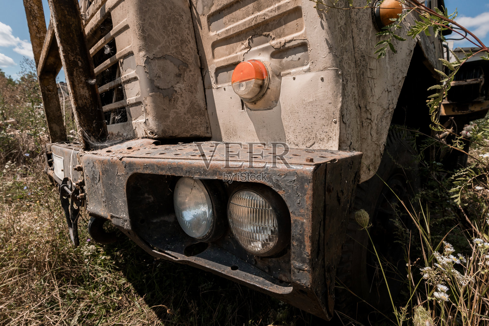 被遗弃的复古卡车前面，生锈且长满杂草照片摄影图片