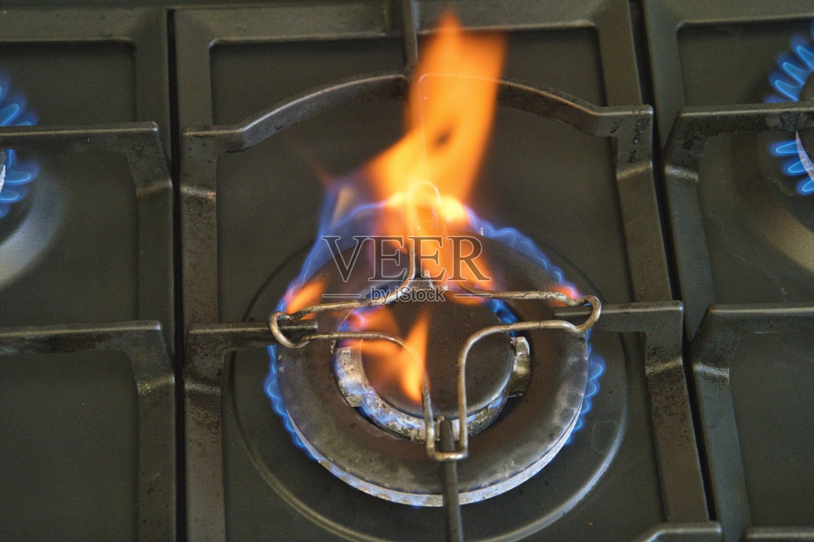 蓝色火焰在燃气灶上跳动，烹饪活动中。照片摄影图片
