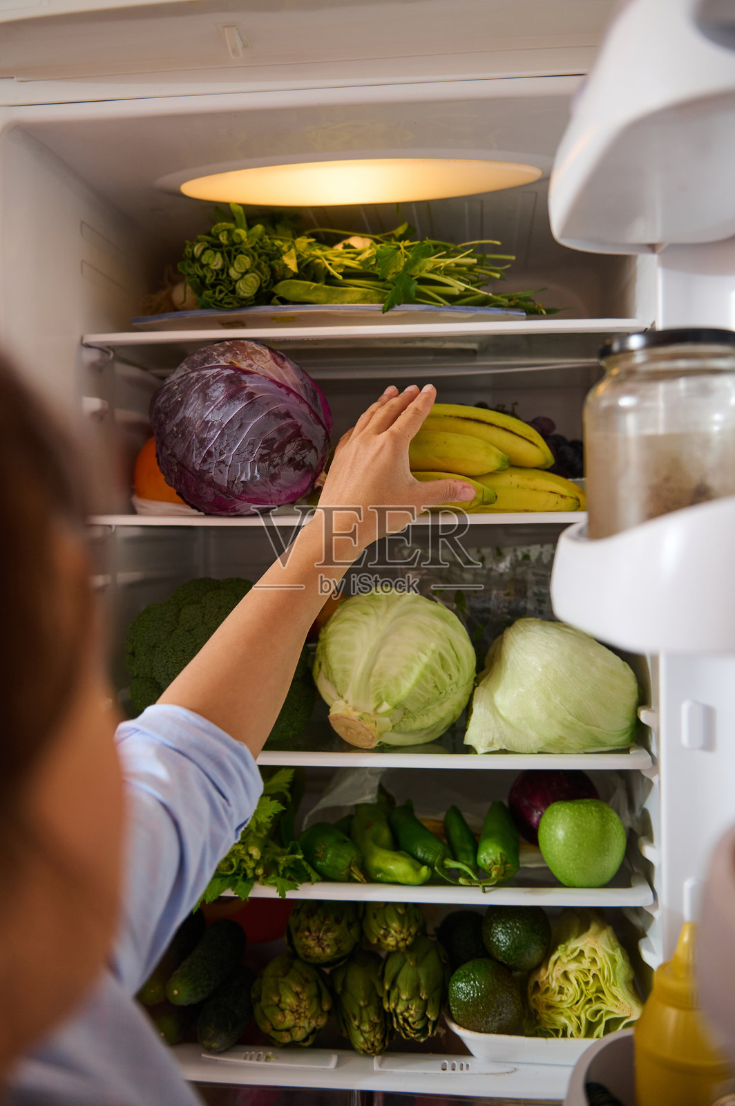 一个人伸手进入装满新鲜农产品的冰箱照片摄影图片