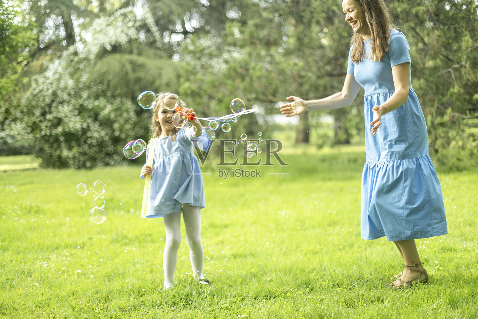 小女孩在公园里和妈妈一起做肥皂泡泡照片摄影图片