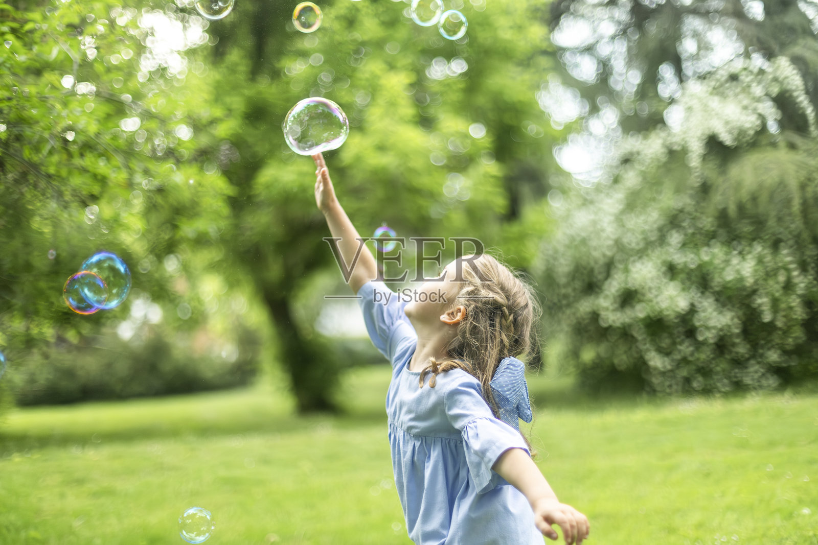 小女孩在绿色公园里玩肥皂泡泡照片摄影图片