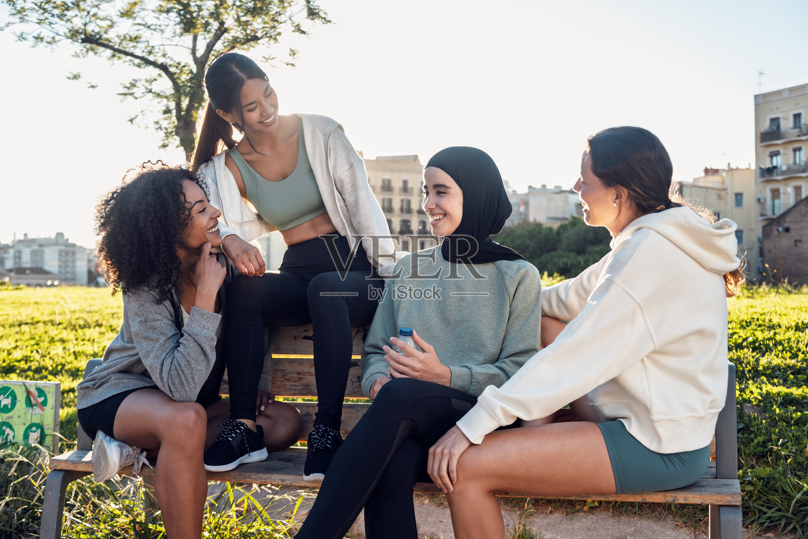 漂亮的运动女性在公园里跑步后，愉快地交谈并对着镜头摆姿势。照片摄影图片