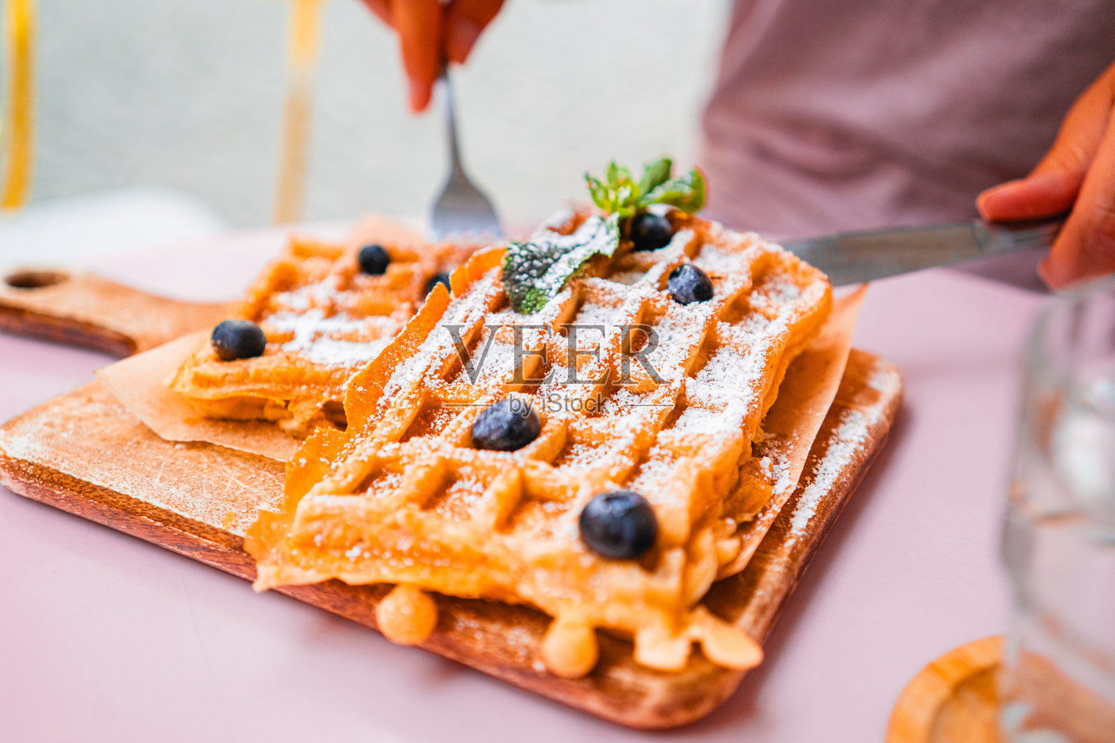美味的比利时华夫饼，上面放着新鲜的蓝莓和糖粉，正在木制餐盘上准备，适合享用美味的早餐或早午餐。照片摄影图片