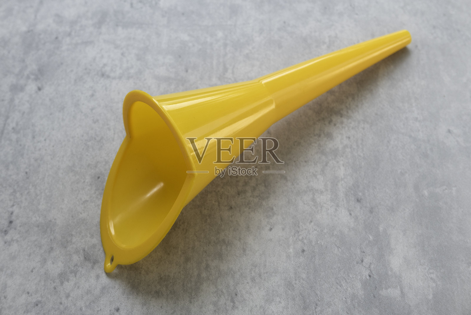灰色背景上的黄色塑料水燃料气漏斗，带喷嘴照片摄影图片