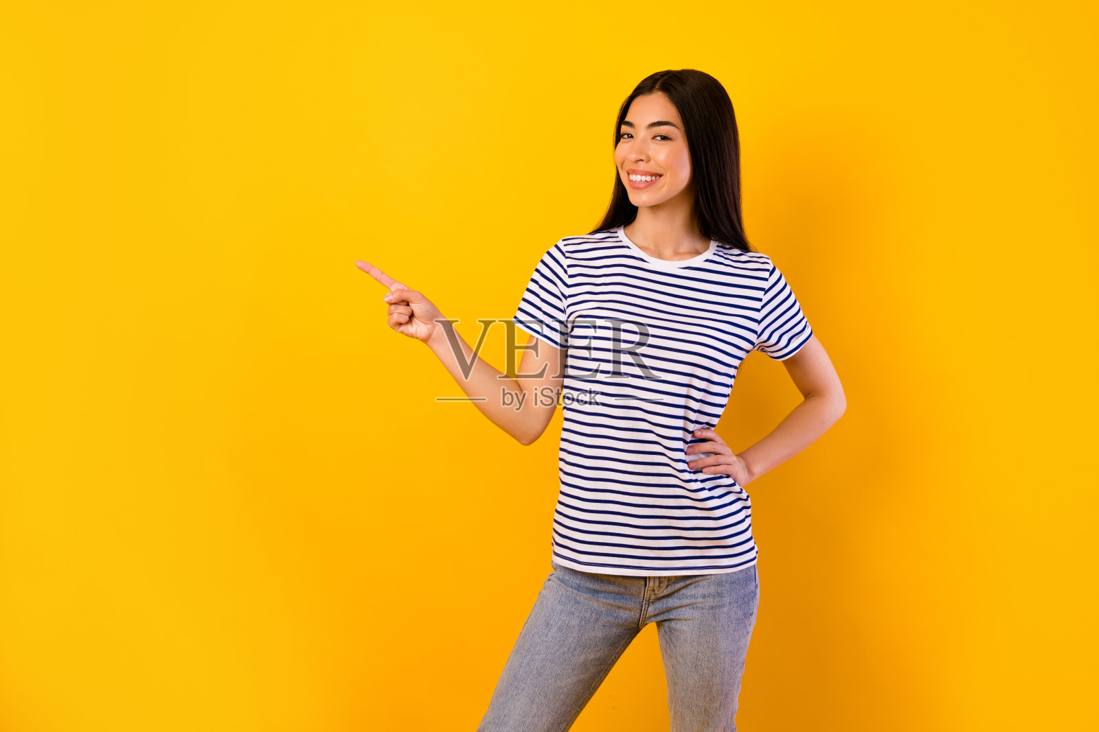 微笑的泰国女孩用手指指向空白空间，背景为黄色。照片摄影图片