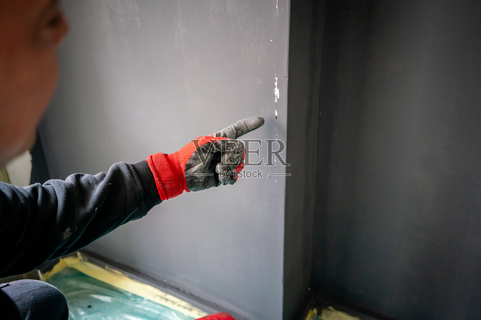 男性画家正在为修缮中的房屋的墙壁签名。照片摄影图片