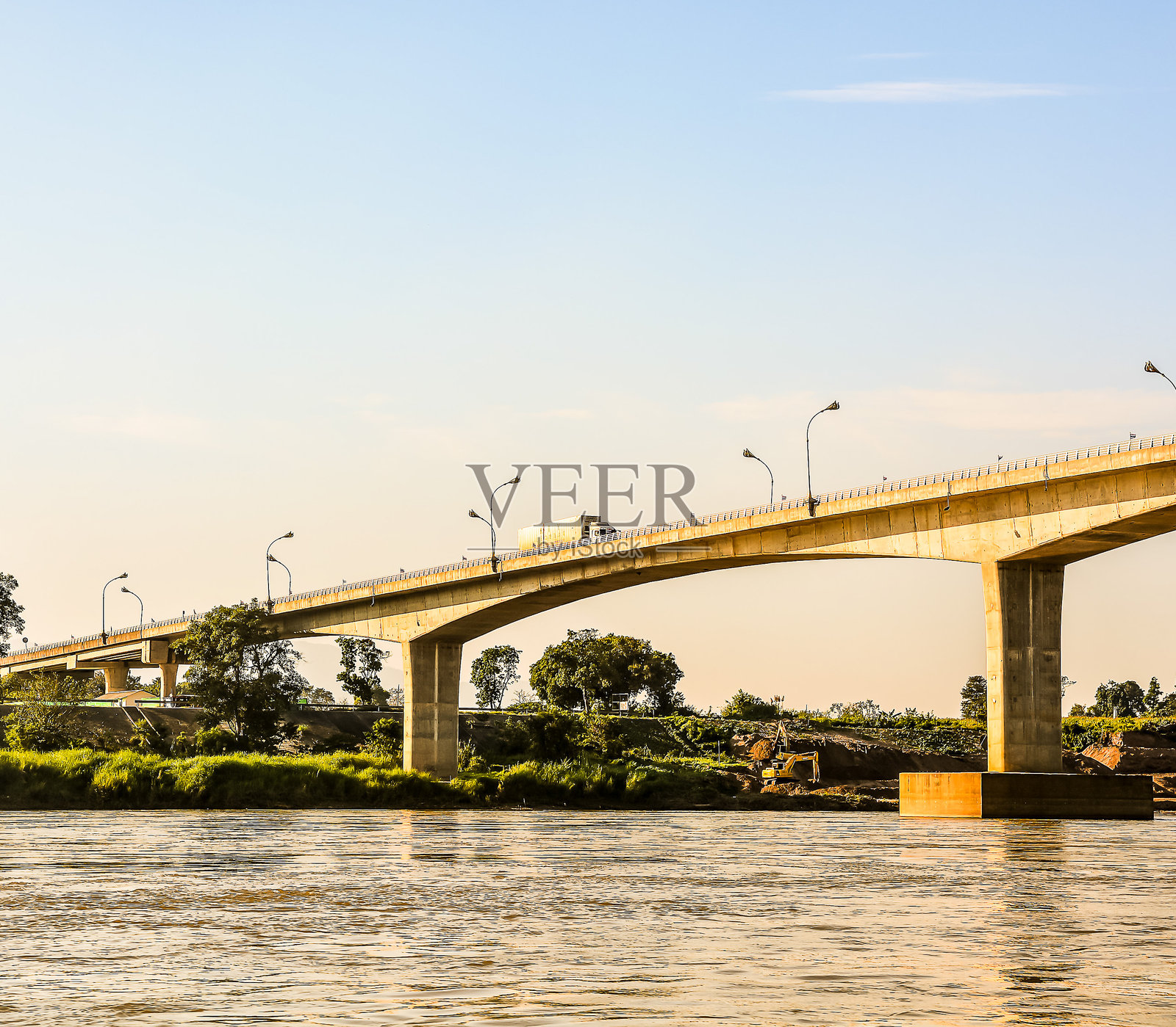 一座桥横跨河流，一辆卡车正在桥上行驶。照片摄影图片