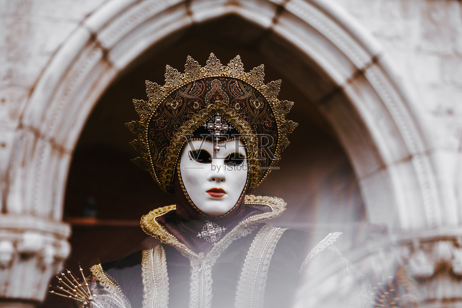 身穿黑色和金色服装、佩戴白色面具的女性肖像，拍摄于威尼斯狂欢节期间照片摄影图片